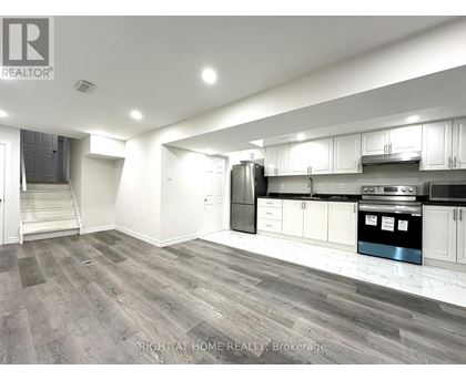 A spacious kitchen with white cabinets and a stainless steel refrigerator.