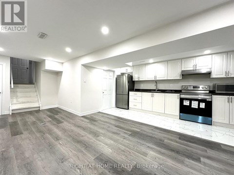 A spacious kitchen with white cabinets and a stainless steel refrigerator.