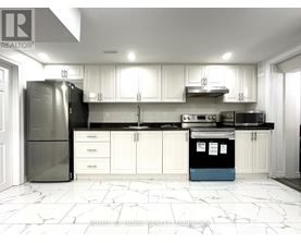A kitchen with white cabinets and a black fridge.