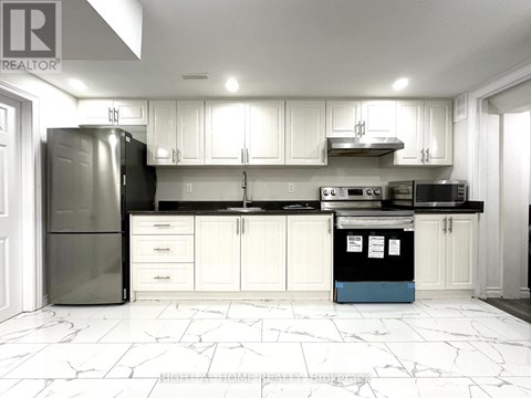 A kitchen with white cabinets and a black fridge.