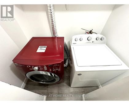 A red washing machine sits next to a white dryer in a small laundry room.