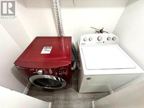 A red washing machine sits next to a white dryer in a small laundry room.