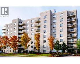 A large apartment building with balconies and trees in front.
