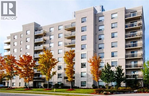 A large apartment building with balconies and trees in front.