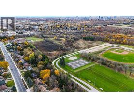 A park with a baseball field and a road running through a residential area.