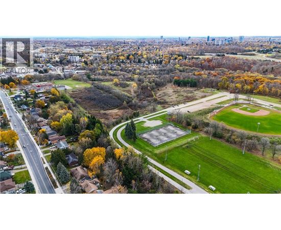 A park with a baseball field and a road running through a residential area.