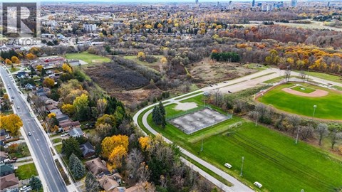 A park with a baseball field and a road running through a residential area.