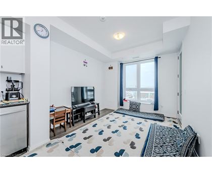 A living room with a television, a sofa, and a rug with a heart pattern.
