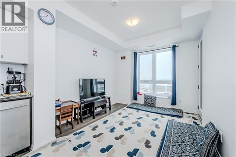 A living room with a television, a sofa, and a rug with a heart pattern.