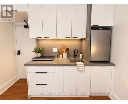 A kitchen with white cabinets and a stainless steel refrigerator.