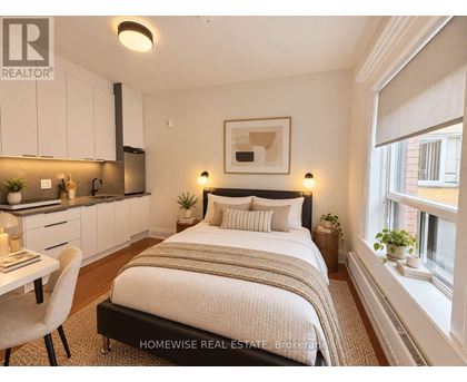 A bedroom with a bed, chair, and a framed picture on the wall.