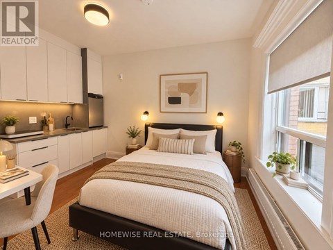 A bedroom with a bed, chair, and a framed picture on the wall.