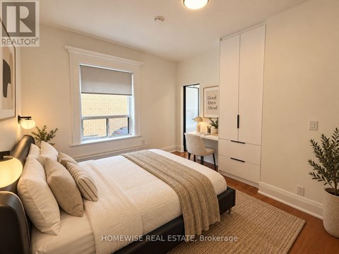 A bedroom with a large bed and a desk with a chair.