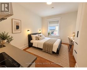A bedroom with a bed, chair, and window.