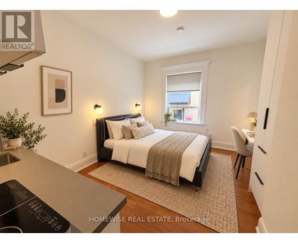 A bedroom with a bed, chair, and window.