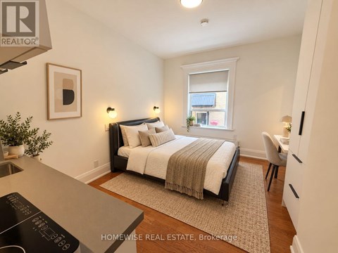 A bedroom with a bed, chair, and window.