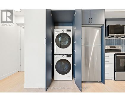 A modern kitchen with a washer and dryer built into the cabinetry.