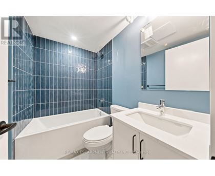A blue tiled bathroom with a white tub, toilet and sink.