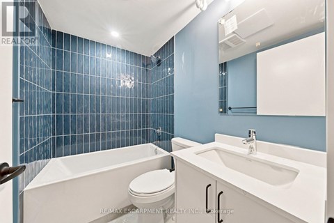 A blue tiled bathroom with a white tub, toilet and sink.