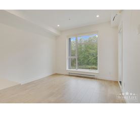 A spacious room with a large window and wooden flooring.