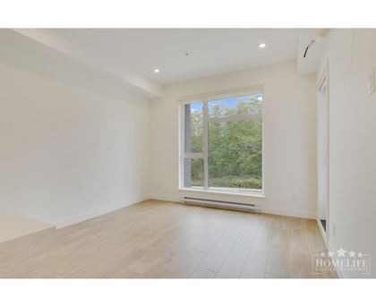 A spacious room with a large window and wooden flooring.
