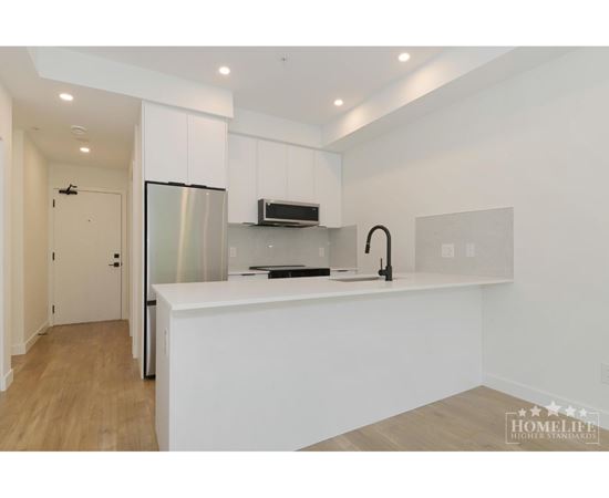 A modern kitchen with white cabinets and a stainless steel refrigerator.