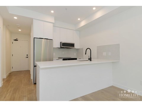 A modern kitchen with white cabinets and a stainless steel refrigerator.