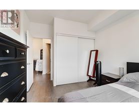 A bedroom with a black dresser and a white bed.