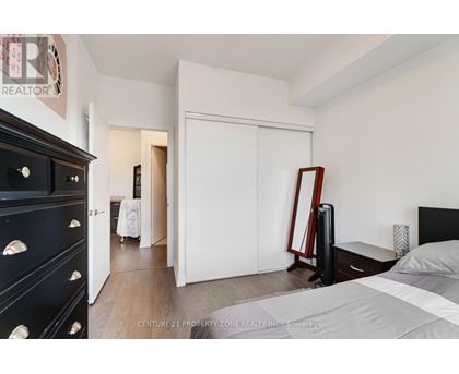A bedroom with a black dresser and a white bed.
