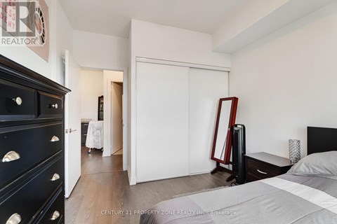 A bedroom with a black dresser and a white bed.