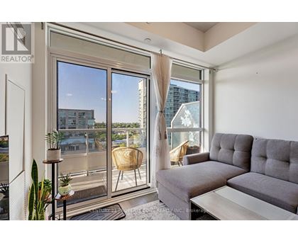 A living room with a grey couch and a large window overlooking a cityscape.