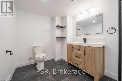 A bathroom with a toilet, sink, and mirror.