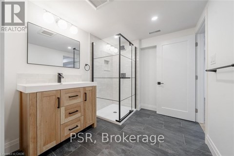 A bathroom with a wooden vanity and a walk-in shower.