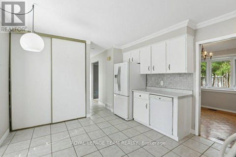 A kitchen with white cabinets and a tile floor.