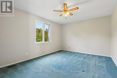 A room with a ceiling fan and a window showing trees outside.