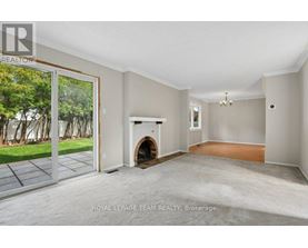 A spacious room with a fireplace and sliding glass doors leading to a garden.