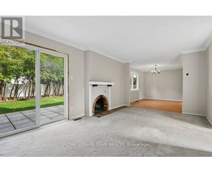 A spacious room with a fireplace and sliding glass doors leading to a garden.