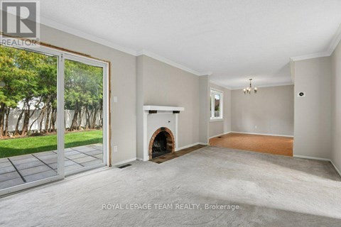 A spacious room with a fireplace and sliding glass doors leading to a garden.