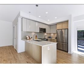 A modern kitchen with a wooden floor and stainless steel appliances.