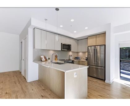 A modern kitchen with a wooden floor and stainless steel appliances.
