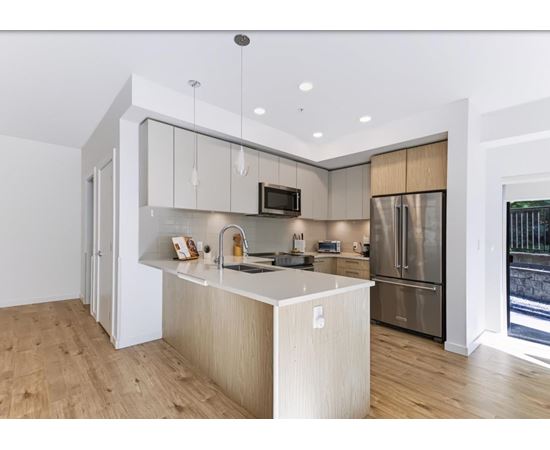 A modern kitchen with a wooden floor and stainless steel appliances.