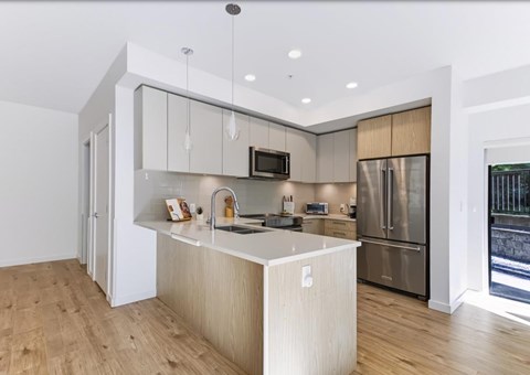 A modern kitchen with a wooden floor and stainless steel appliances.