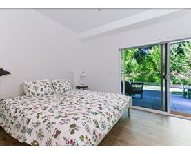 A bedroom with a floral bedspread and a sliding glass door.