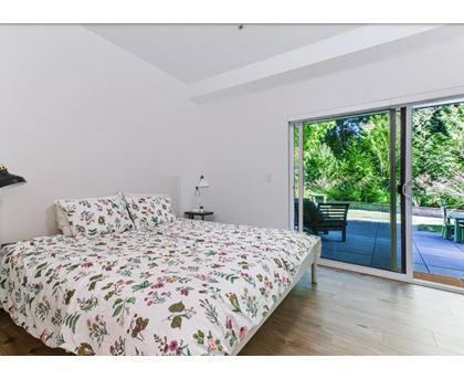 A bedroom with a floral bedspread and a sliding glass door.