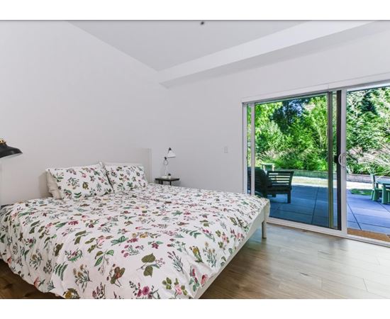 A bedroom with a floral bedspread and a sliding glass door.