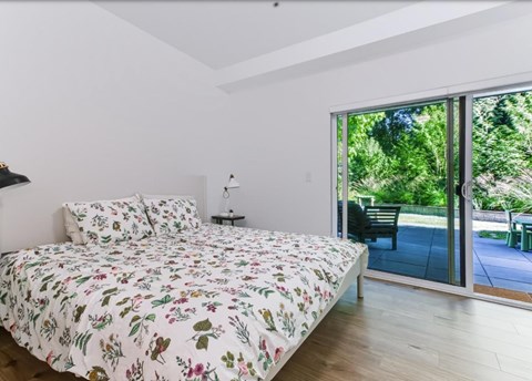 A bedroom with a floral bedspread and a sliding glass door.