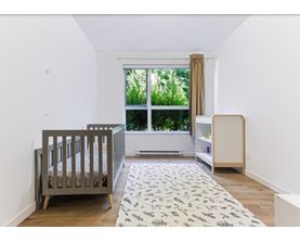 A baby's room with a crib, changing table, and a window with a view of trees.