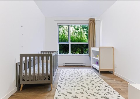 A baby's room with a crib, changing table, and a window with a view of trees.