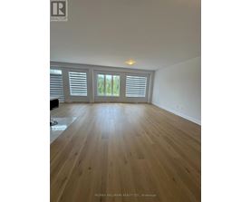 A spacious room with wooden flooring and white walls.