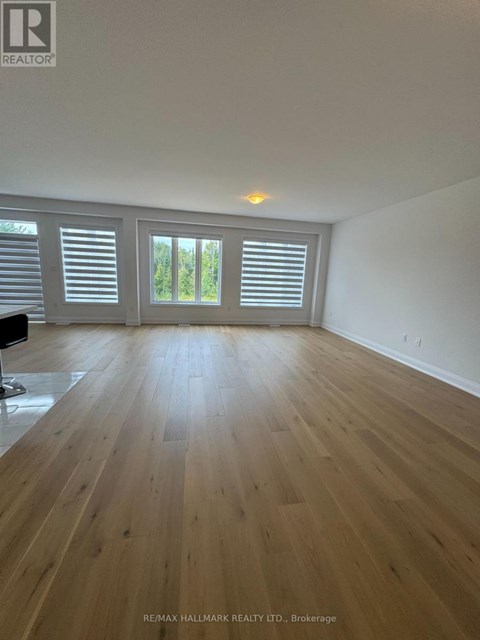 A spacious room with wooden flooring and white walls.